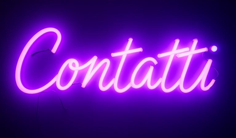 Insegna al neon con la parola 'Contatti' in stile artistico e moderno, illuminata con luce viola e blu.